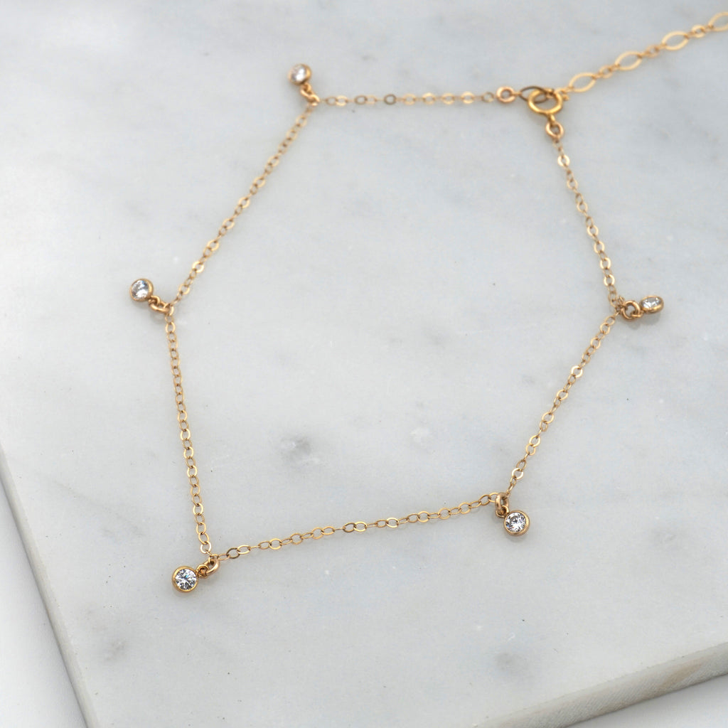 The 5-stone anklet.  Has a gold chain and five clear gemstones, with a dangling chain.