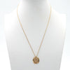 A sleek, modern gold chain with a coin pendant on it that has a design of angel wings seen from the back.